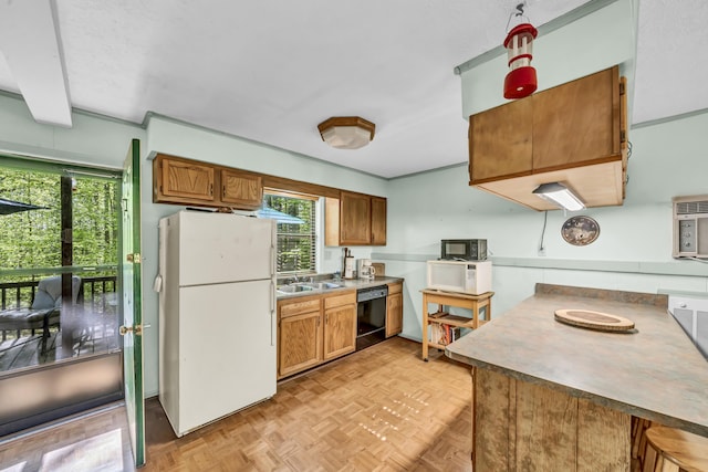 kitchen featuring brown cabinetry, a sink, black appliances, and a wealth of natural light
