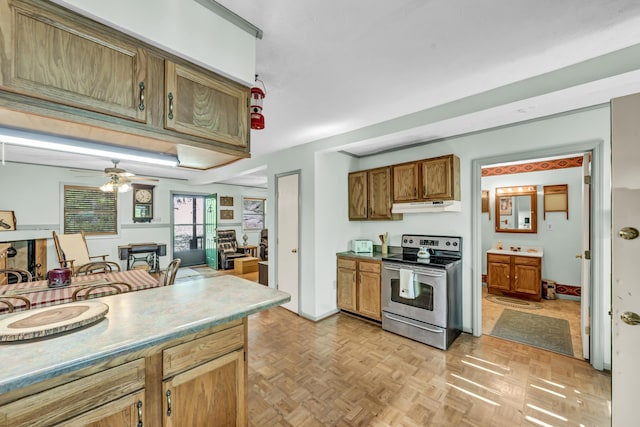 kitchen with ceiling fan, under cabinet range hood, brown cabinets, and stainless steel range with electric stovetop