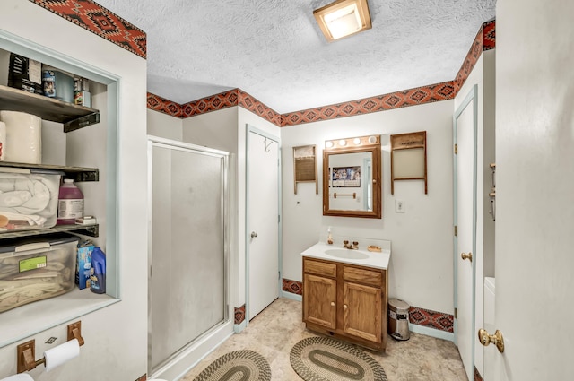 full bath with vanity, a textured ceiling, baseboards, and a stall shower