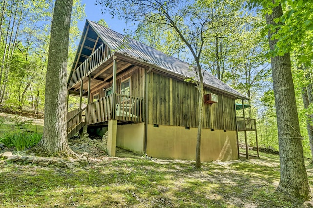 view of side of home with board and batten siding, a wooden deck, and metal roof