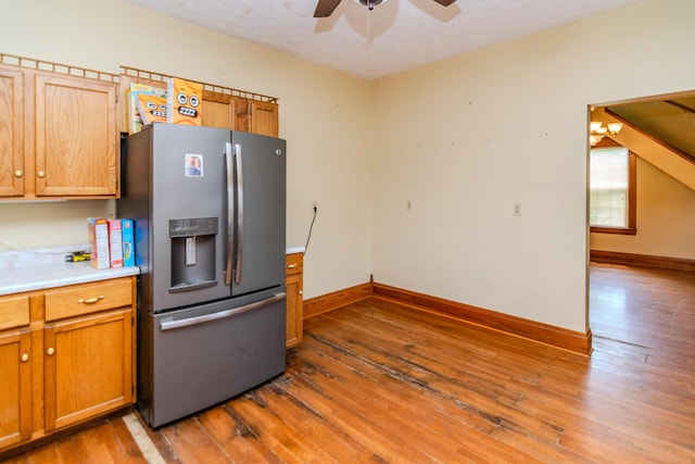 kitchen featuring stainless steel fridge, ceiling fan, hardwood / wood-style flooring, light countertops, and baseboards