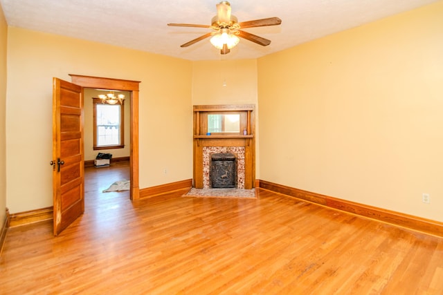 unfurnished living room featuring light wood-style flooring, baseboards, a fireplace, and ceiling fan