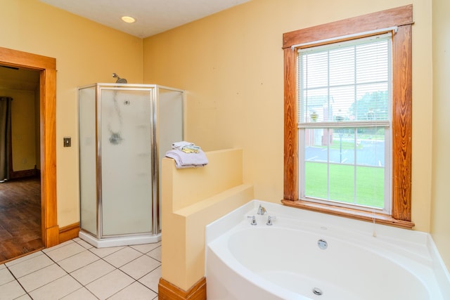 bathroom with healthy amount of natural light, a stall shower, and a garden tub
