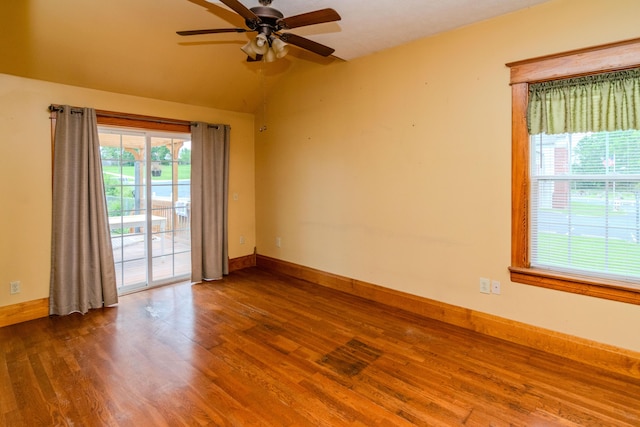empty room with a ceiling fan, wood finished floors, vaulted ceiling, and baseboards