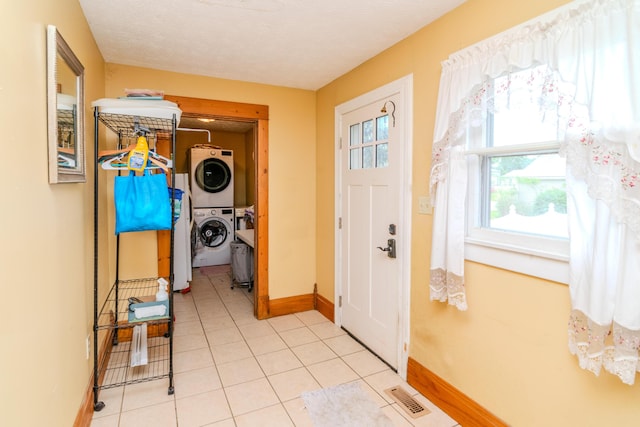 foyer with stacked washer and clothes dryer, baseboards, and light tile patterned floors
