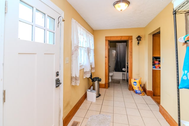 hall featuring baseboards and light tile patterned flooring
