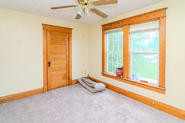 spare room with carpet floors, baseboards, a ceiling fan, and a textured ceiling