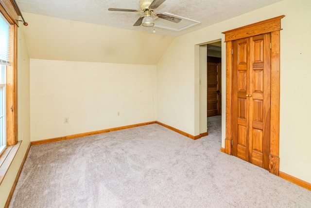 additional living space featuring lofted ceiling, ceiling fan, carpet floors, baseboards, and a textured ceiling