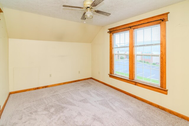 bonus room featuring carpet flooring, lofted ceiling, baseboards, a textured ceiling, and ceiling fan