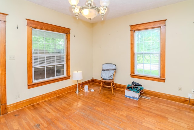 empty room featuring a chandelier, wood finished floors, and healthy amount of natural light