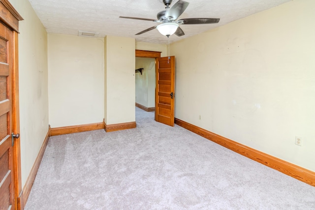 carpeted empty room featuring ceiling fan, a textured ceiling, and baseboards