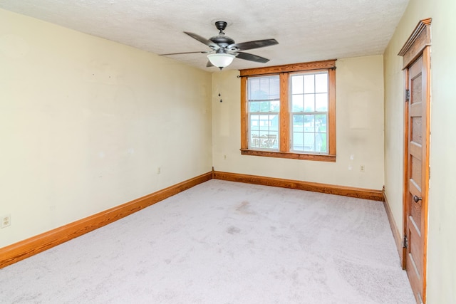 carpeted empty room featuring ceiling fan, baseboards, and a textured ceiling