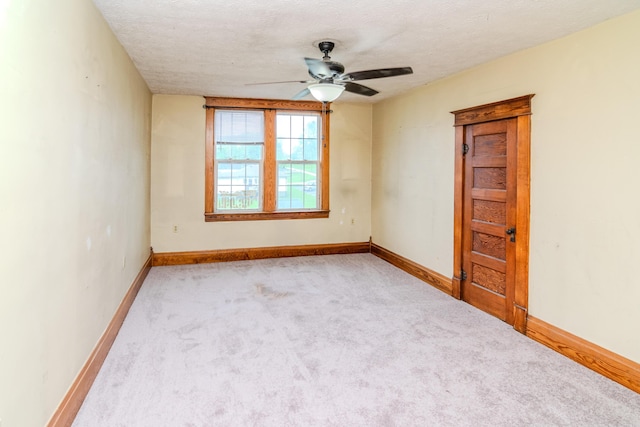 carpeted empty room with ceiling fan, baseboards, and a textured ceiling