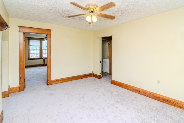 carpeted empty room featuring baseboards, ceiling fan, and a textured ceiling