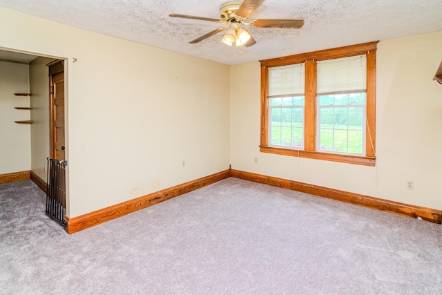 carpeted spare room with a textured ceiling, a ceiling fan, and baseboards