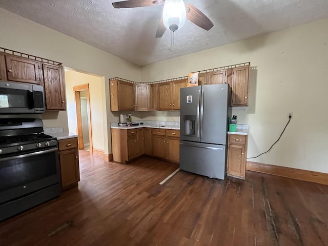 kitchen featuring appliances with stainless steel finishes, light countertops, dark wood-style flooring, baseboards, and a ceiling fan