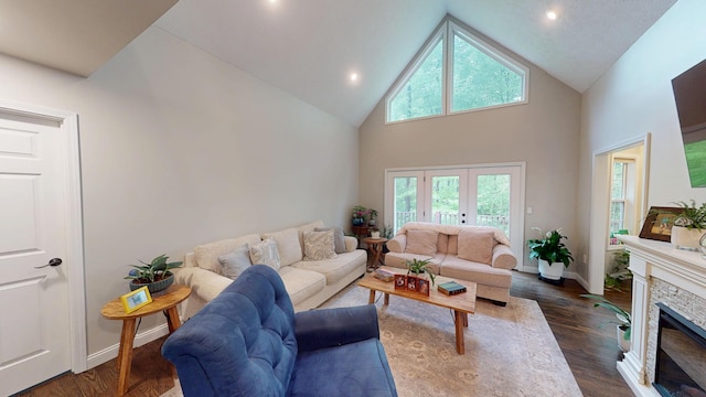 living room featuring high vaulted ceiling, a stone fireplace, dark wood-style flooring, and baseboards
