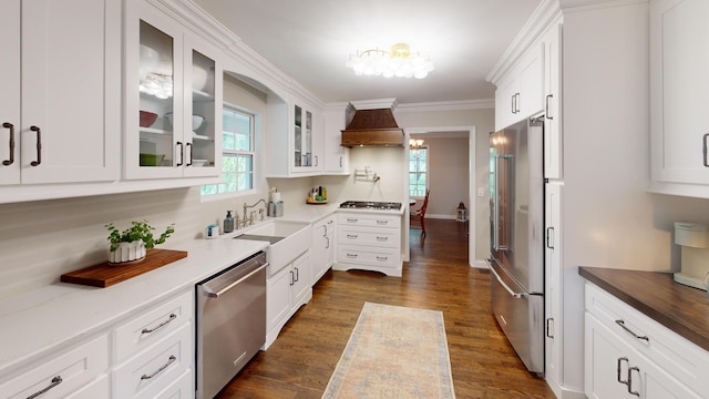 kitchen featuring a sink, a chandelier, premium range hood, white cabinets, and appliances with stainless steel finishes