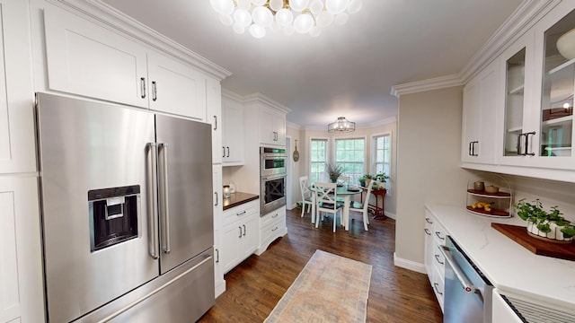 kitchen featuring white cabinetry, baseboards, stainless steel appliances, and a notable chandelier