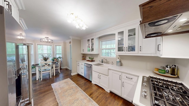 kitchen featuring an inviting chandelier, appliances with stainless steel finishes, a sink, white cabinetry, and crown molding