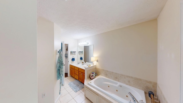 bathroom with tile patterned floors, a tub with jets, a textured ceiling, and vanity
