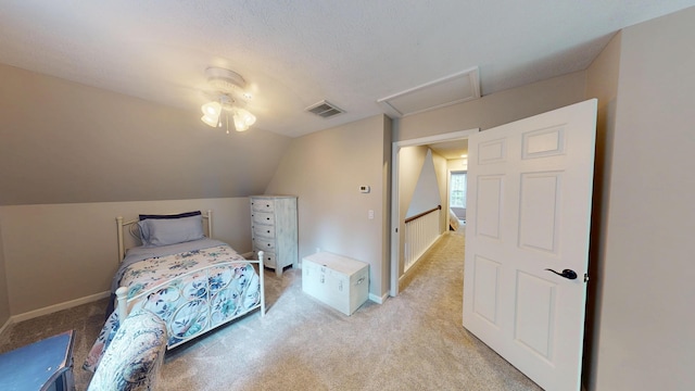 bedroom featuring attic access, visible vents, vaulted ceiling, and light colored carpet