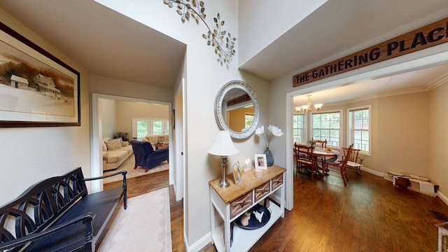 hall with a chandelier, baseboards, and wood finished floors