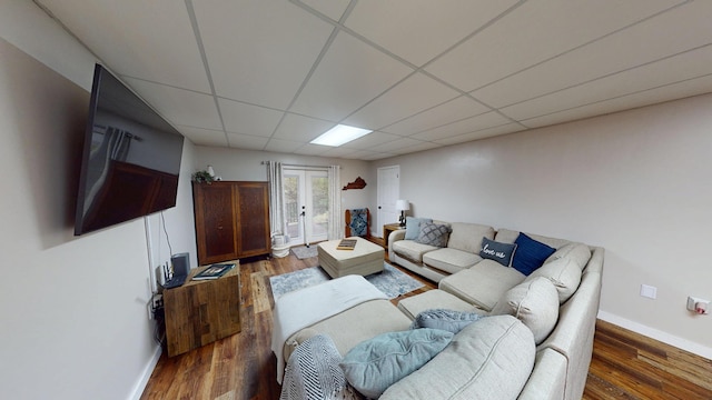 living area with wood finished floors, french doors, a drop ceiling, and baseboards