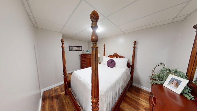 bedroom with wood finished floors, a drop ceiling, and baseboards