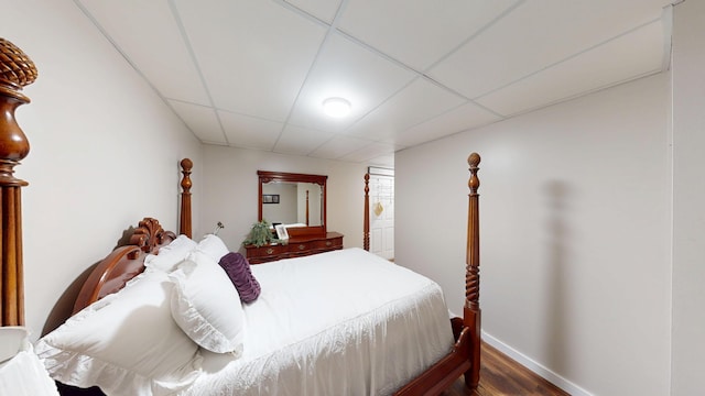 bedroom featuring dark wood-style flooring, a paneled ceiling, and baseboards