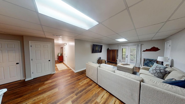 living room featuring baseboards, visible vents, wood finished floors, and a drop ceiling