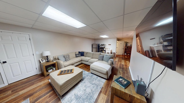 living area with a paneled ceiling and wood finished floors