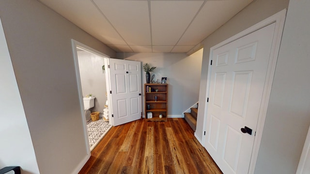 hall with stairway, a drop ceiling, and wood finished floors