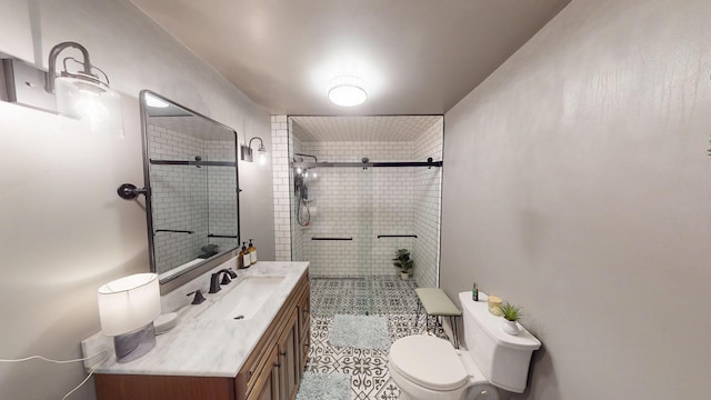 bathroom featuring toilet, tile patterned floors, tiled shower, and vanity