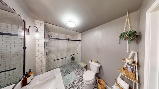 bathroom with a tile shower, toilet, and vanity