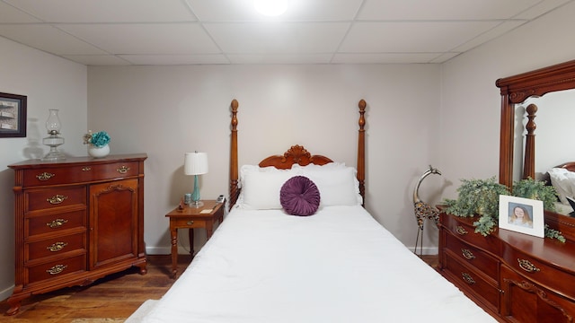 bedroom featuring dark wood-style floors, baseboards, and a paneled ceiling