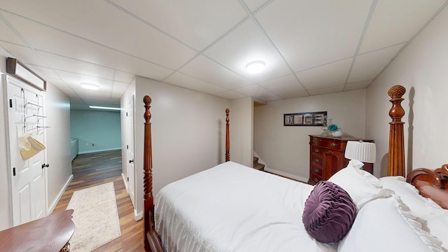 bedroom featuring a paneled ceiling, wood finished floors, and baseboards