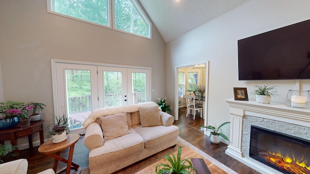 living room with a chandelier, dark wood-style flooring, a fireplace, high vaulted ceiling, and french doors