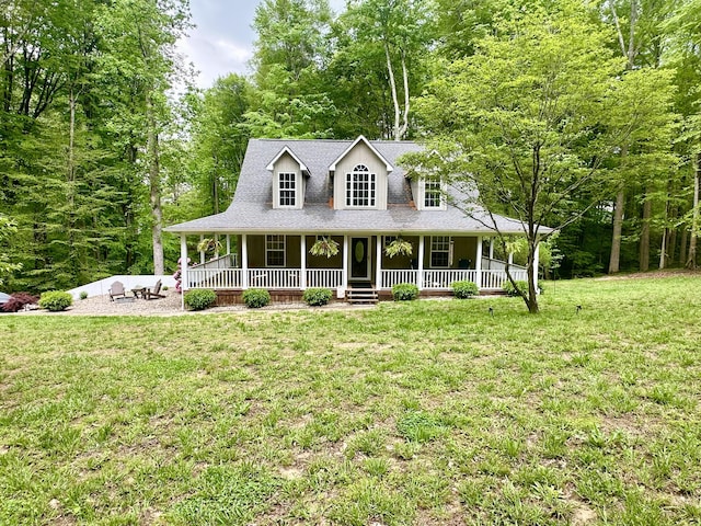 farmhouse inspired home with a front lawn, a shingled roof, covered porch, and a view of trees