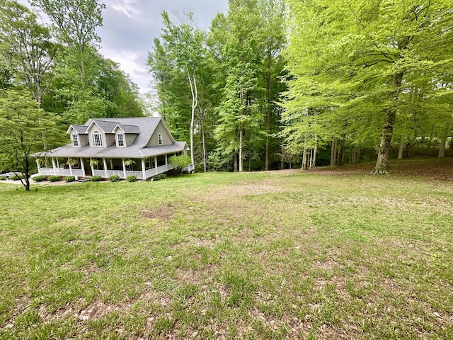 view of yard with covered porch and a view of trees