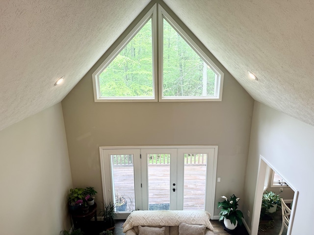 living room featuring a textured ceiling, french doors, and high vaulted ceiling