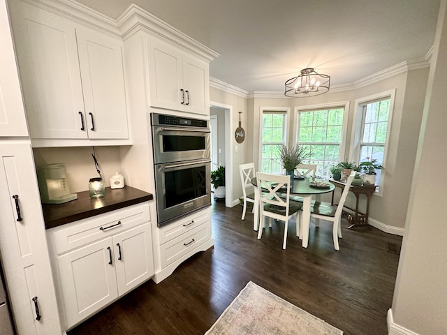 kitchen featuring dark wood-style floors, an inviting chandelier, dark countertops, baseboards, and double oven
