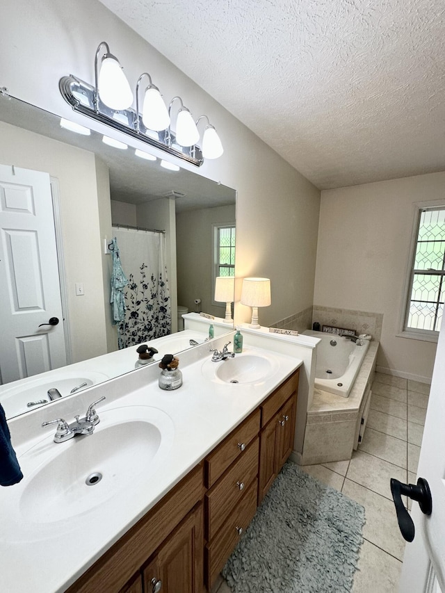 bathroom with tile patterned floors, a tub with jets, a textured ceiling, and a sink