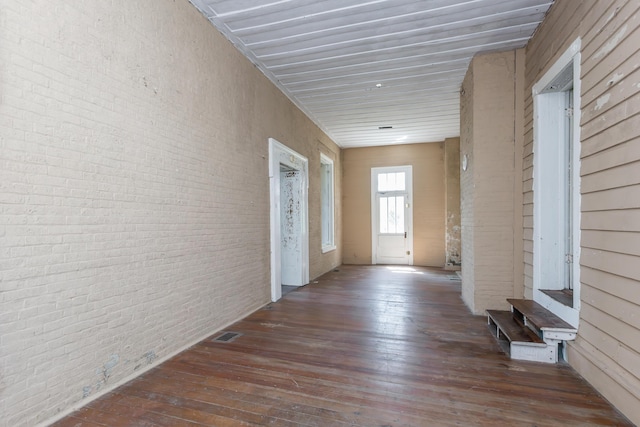 hall featuring brick wall, visible vents, and hardwood / wood-style flooring
