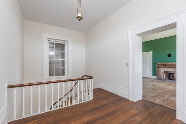 hallway featuring baseboards, an upstairs landing, and hardwood / wood-style flooring