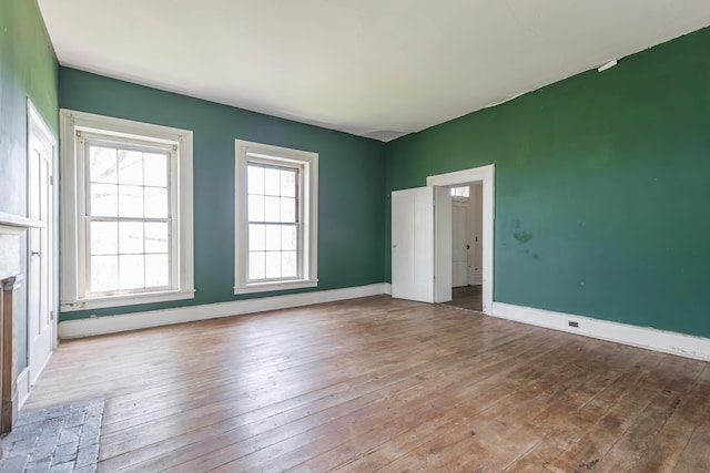 spare room with a fireplace, baseboards, and wood-type flooring