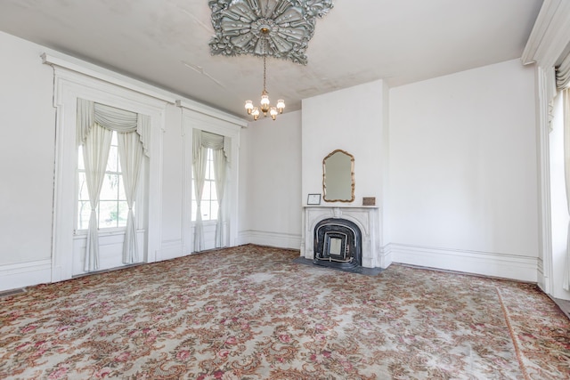 unfurnished living room with baseboards, a fireplace with flush hearth, carpet, and a notable chandelier