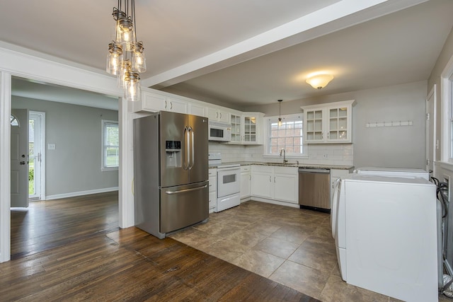 kitchen featuring a sink, stainless steel appliances, decorative backsplash, glass insert cabinets, and washer / dryer