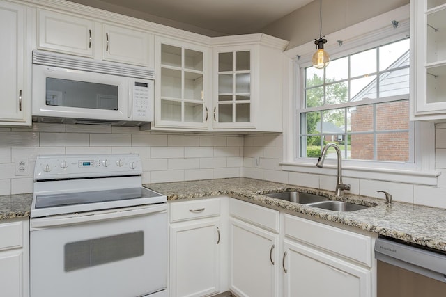 kitchen featuring pendant lighting, decorative backsplash, white cabinets, a sink, and white appliances