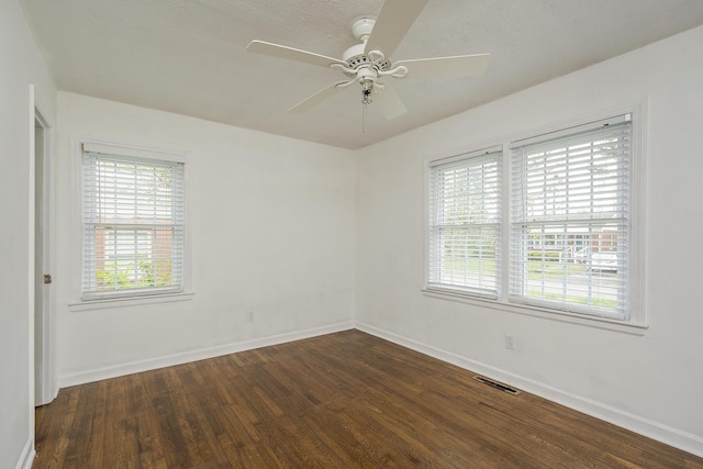spare room with a ceiling fan, visible vents, wood finished floors, and baseboards